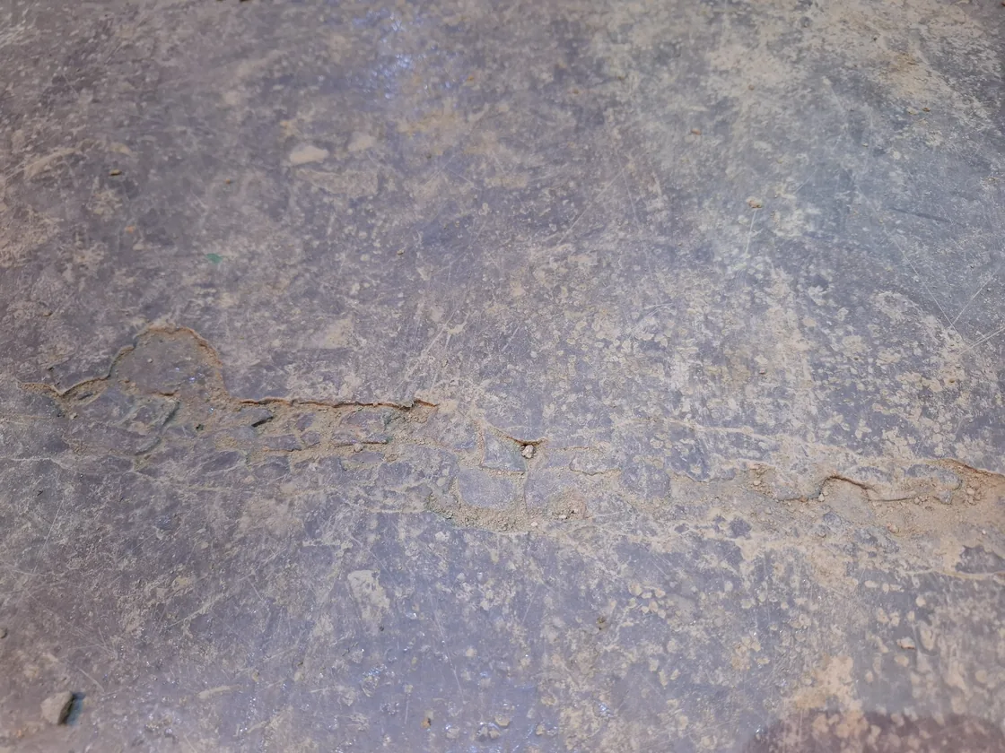Piso industrial de hormigón desgastado, picado y con una grieta